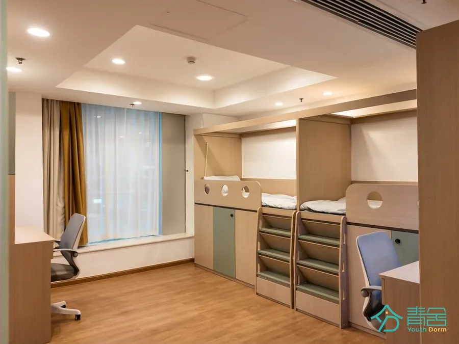 Quad room at the Sheung Wan Dorm (Youth Dorm) with raised beds, storage steps, desks and chairs